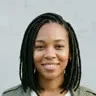 Photo de la personne qui reconnaît : une femme souriante avec des tresses, une veste olive et un t-shirt blanc