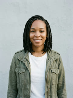 Photo of the one who still knows them: a smiling woman with braids in an olive jacket and white T-shirt