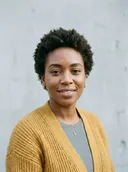 Photo de la personne qui reconnaît : une femme souriante aux cheveux courts bouclés en cardigan moutarde
