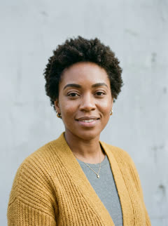 Photo of the one who still knows them: a smiling woman with short curly hair in a mustard cardigan