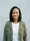 Photo de la personne qui reconnaît : une femme souriante avec des tresses, une veste olive et un t-shirt blanc