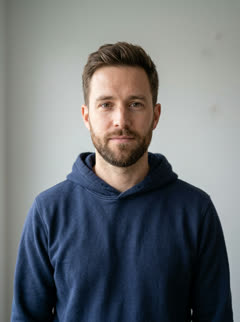 Photo of the one who turns: a bearded man in a navy hoodie against a grey wall